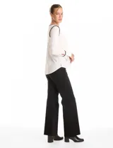 Blusa de crepe negro con ribetes en color beige que recorren el escote, la línea central y las costuras de los hombros. Presenta cuello redondo con abertura en V, mangas largas con puños abiertos y detalle de botón metálico, y ruedo redondeado.