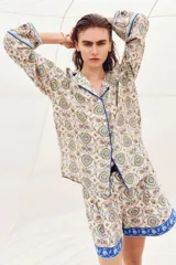 Short holgado de mezcla de lino, con estampado paisley en tonos beige, azul y amarillo, cintura elástica con pliegues, bolsillos laterales al bies y una franja azul con diseño floral en el ruedo. Incluye un cinturón trenzado fino con hebilla metálica.