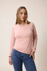 Remera de manga larga color rosado, con cuello redondo y puños con detalle de volados fruncidos.