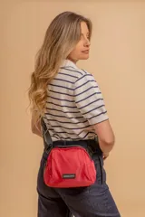 Bandolera pequeña de diseño moderno, confeccionada en tafeta liviana y resistente. Cuenta con cierre superior, correa ancha ajustable y logo frontal de la marca.