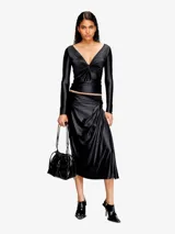 Bolso tipo cubo Diesel Scrunch-D, color gris oscuro, confeccionado en cuero brillante con efecto arrugado. Presenta logo metálico "D" en el frente, cierre con cordones ajustables, correa de hombro extraíble y múltiples bolsillos internos.