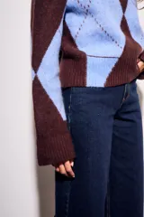 Sweater de tejido de punto con diseño de rombos (argyle) en tonos azul claro y marrón oscuro. Presenta cuello redondo y puños y cintura acanalados.