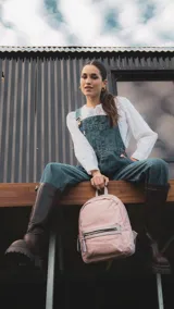 Mochila mediana color rosa, de nylon con detalles en símil cuero en el bolsillo frontal. Tiene asa de mano y correas regulables.