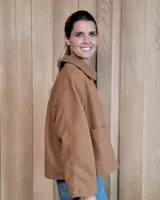 Chaqueta de textura bouclé en color bordó, con corte oversize, cuello camisero, cierre frontal y bolsillos laterales.