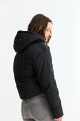 Campera puffer corta de color negro, con capucha, cierre frontal con cremallera y solapa con botones a presión.