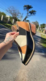 Zapatos de cuero negro con paneles texturizados, punta fina, taco cuadrado y elásticos laterales para mayor comodidad.