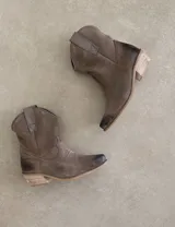 Bota corta estilo western de cuero color marrón, con taco cuadrado de 5 cm y diseño clásico. Presenta un acabado desgastado en la puntera y el talón.