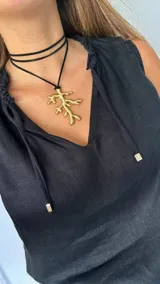 Collar con cordón marrón y dije dorado en forma de rama.