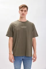 Remera manga corta oversize color verde militar con estampa de texto en gris en el pecho.