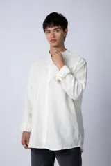 Camisa de lino color blanco con cuello mao y cierre frontal de botones. Presenta mangas largas con puños simples y un corte clásico.