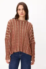 Sweater de punto con diseño de rayas verticales en relieve y textura trenzada, color terracota y beige. Presenta cuello redondo, corte holgado y diseño cropped.