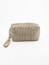 Necessaire de mano con diseño texturizado de puntos en relieve, combinando colores beige y blanco. Cuenta con cierre superior y una correa de muñeca a juego.