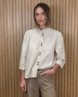 Camisa de algodón color blanco, con cuello alto con volados, mangas tres cuartos con detalles de bordado ingles y cierre frontal con botones de nácar.