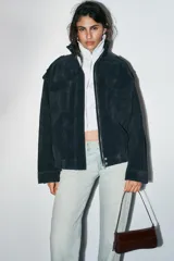 Bolso de hombro con solapa y acabado efecto acharolado. Cuenta con asa ajustable y cierre mediante imán.