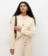 Buzo de punto con capucha y cordones ajustables con punteras metálicas. Presenta un diseño de corte regular, confeccionado en una mezcla de viscosa, poliéster y poliamida, ofreciendo una textura suave y cómoda.