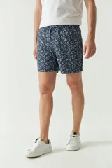 Short de baño con estampado botánico de hojas en tonos azul y gris. Presenta cintura elástica con cordón ajustable, dos bolsillos laterales, un bolsillo trasero y logo bordado.