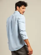 Camisa celeste de manga larga con cuello abotonado y bolsillo en el pecho.