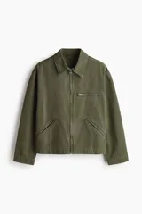 Campera de algodón en color verde militar, con cuello camisero, cierre frontal, un bolsillo superior con cierre y dos bolsillos laterales ribeteados.