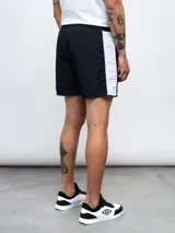 Short de baño negro con una banda vertical blanca en el lateral con el logo de Umbro en color rosa.