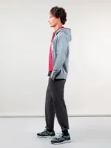 Sudadera gris con capucha ajustable con cordones blancos, cierre frontal con cremallera, bolsillos tipo canguro y logo bordado en el pecho.