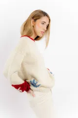 Buzo tejido de lana merino color marfil, con diseño de jinete cowboy en la espalda y detalles en rojo y amarillo en cuello y puños.