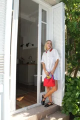 Camisa de lino color verde brillante, de corte holgado y manga corta. Presenta cuello tejido con patrón de cuadros en blanco y negro, y botones frontales de colores variados.