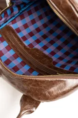 Mochila de cuero sintético marrón con efecto craquelado, asa superior y placa metálica frontal con el logo de la marca.