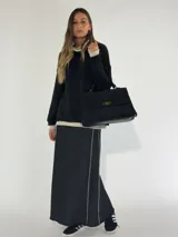 Cartera negra de gamuza con flecos y cierre metálico dorado.