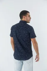 Camisa de hombre Mistral con look lino, de manga corta y corte slim. Presenta un estampado lineal de flores en color azul sobre fondo blanco, cartera abotonada y logo bordado en el pecho.