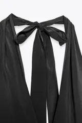 Vestido midi negro de tejido fluido, con cuello halter que se anuda en la nuca y escote pronunciado en pico.