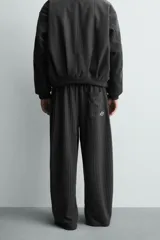 Pantalón de corte baggy fit, color gris oscuro con estampado de rayas verticales finas. Presenta cintura elástica con cordón interior, bolsillos frontales de vivo y bolsillos traseros de plastrón.