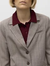 Blazer de corte regular con cuello sastrero y cierre frontal de botones. Presenta puños abotonados y está confeccionado en tejido plano con estampado de cuadros en tonos beige, negro y bordó.