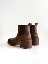 Bota tipo chelsea de cuero color chocolate con acabado texturizado, plataforma y taco cuadrado. Presenta paneles elásticos laterales en color negro.