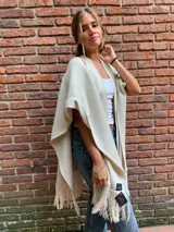 Ruana color crema de tejido de punto fino en lana con detalles en cuero y flecos.