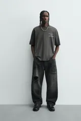 Camiseta de manga corta y cuello redondo, color gris oscuro o negro deslavado, con estampado de texto en blanco en el pecho.