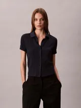 Chomba Calvin Klein de manga corta en color azul marino, con diseño de jacquard geométrico integral, cuello clásico y cierre frontal completo de botones.