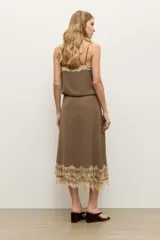 Falda midi color topo, confeccionada en tela fluida, con detalle de encaje en tono crudo en el ruedo.