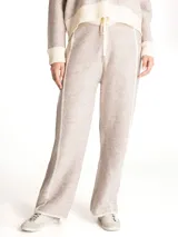 Pantalon de punto color beige con textura jaspeada, corte recto y holgado. Presenta cintura elastizada con cordón de ajuste y detalles de costuras verticales en color crema a lo largo de las piernas.