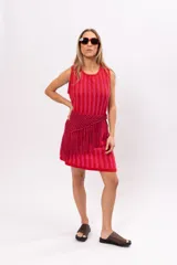 Vestido corto de tejido de punto a rayas verticales en tonos rosa y rojo. Incluye cinturón tejido con flecos.