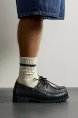 Zapato estilo náutico de piel color negro, de la colección especial Fruit of the Loom x Zara. Presenta detalle de bordón en el empeine, ojalillos metálicos dorados, cordones negros y suela track dentada.