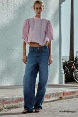 Camisa rosa de cuello alto, mangas cortas abullonadas y detalles de encaje y entredós en el frente y las mangas.