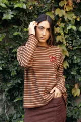 Remerón de manga larga con diseño de rayas horizontales finas en tonos tierra. Presenta un corte holgado y cuenta con un bordado artesanal en color rojo en el pecho.