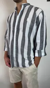 Camisa celeste y blanca a rayas verticales, de lino, con cuello mao y mangas largas con puños.