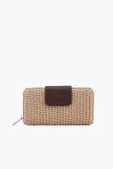 Billetera de rafia color tostado, de formato rectangular y cierre perimetral con cremallera. Cuenta con una solapa frontal de cuero sintético marrón con el logo grabado de la marca.
