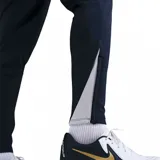 Pantalón de entrenamiento Nike para hombre de la selección uruguaya, color azul marino, con puños ajustados en los tobillos y cordón en la cintura. Presenta el escudo de la AUF con cuatro estrellas bordado en la pierna izquierda y el logo de Nike en blanco en la pierna derecha.