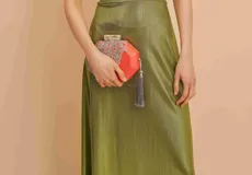 Clutch de mano rígido color coral con bordado floral y borla gris.