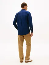 Camisa azul oscuro de corte regular con patrón de raya diplomática blanca y roja, confeccionada en puro algodón Oxford. Cuenta con cuello abotonado, cierre frontal con botones, bolsillo de parche en el pecho con logo bordado y mangas largas con puños abotonados.