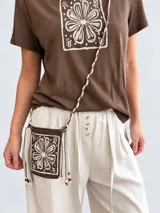 Remera marrón de manga corta y cuello redondo, con estampado floral en un recuadro claro en el frente.