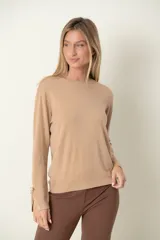 Buzo marrón de punto con cuello redondo y mangas largas. Detalle de puño abierto con moña y perla.