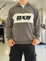 Hoodie de corte clásico con medio cierre y cuello alto, en color marrón con una franja horizontal blanca en el pecho que incluye el logo estampado en negro. Presenta además un pequeño bordado en el hombro izquierdo y puños y cintura elastizados de rib.